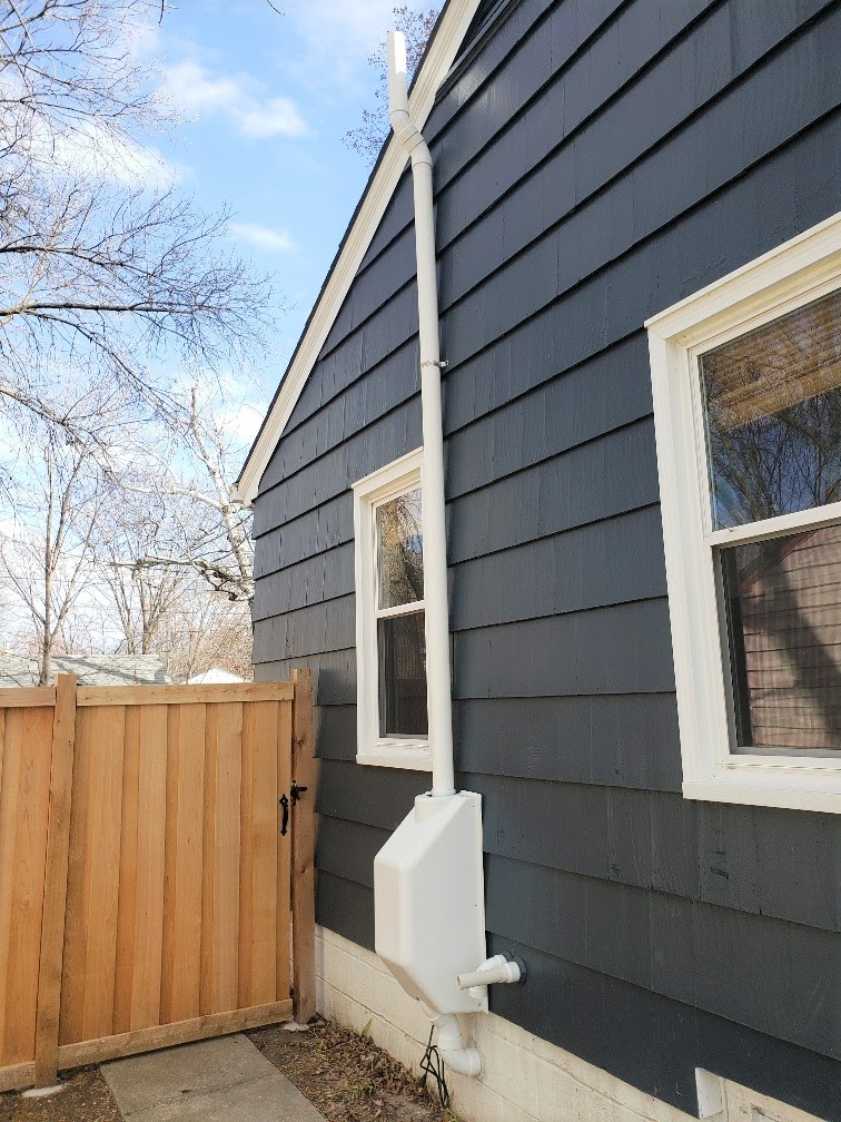 radon mitigation system on a blue house